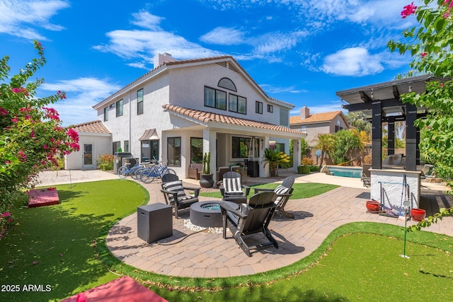 back of property with exterior fireplace, a patio area, and an outdoor fire pit