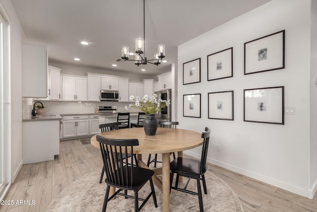 dining space featuring a chandelier, light hardwood / wood-style floors, and sink