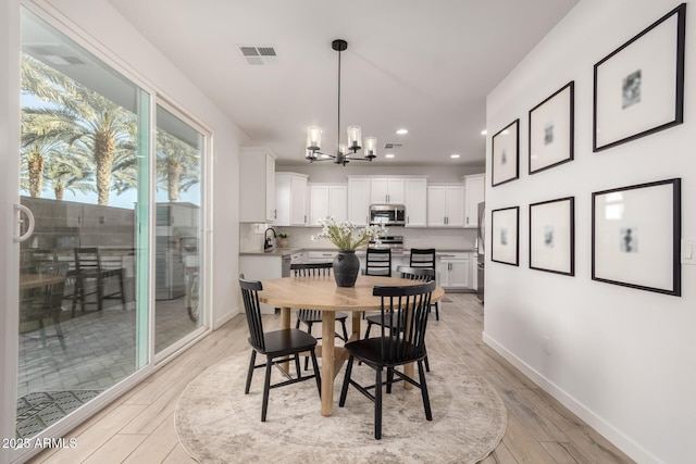 dining room featuring an inviting chandelier, sink, and light hardwood / wood-style flooring