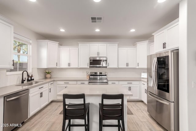 kitchen with sink, stainless steel appliances, a breakfast bar, and white cabinets