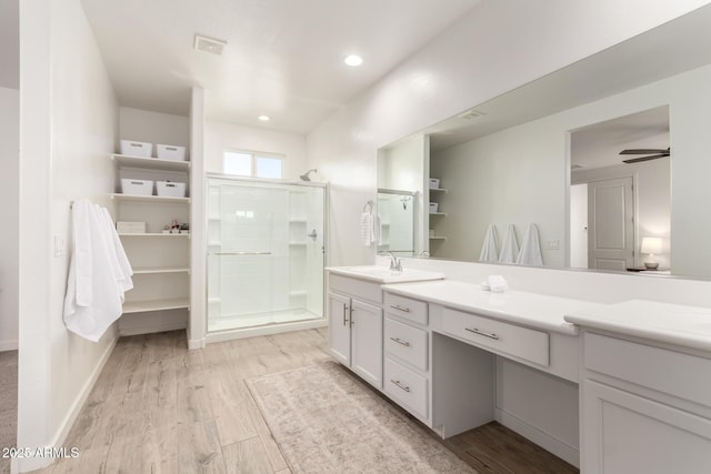 bathroom with wood-type flooring, vanity, and a shower with shower door