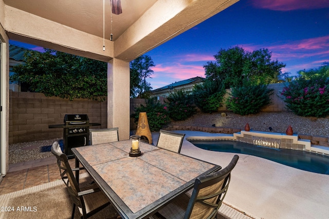 patio terrace at dusk with a fenced in pool and grilling area