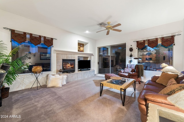 carpeted living room with ceiling fan, built in features, and a tile fireplace