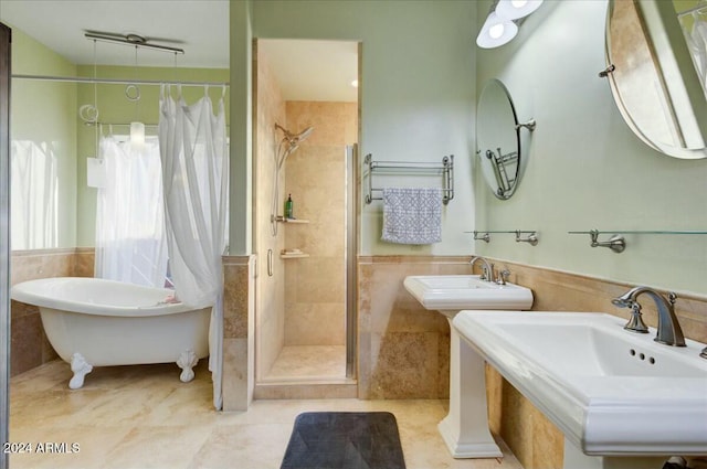 bathroom featuring shower with separate bathtub, tile walls, and double sink