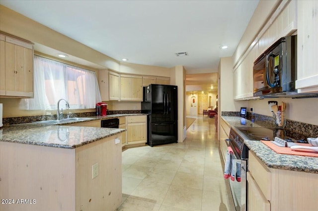 kitchen with light brown cabinets, dark stone counters, black appliances, sink, and light tile patterned floors