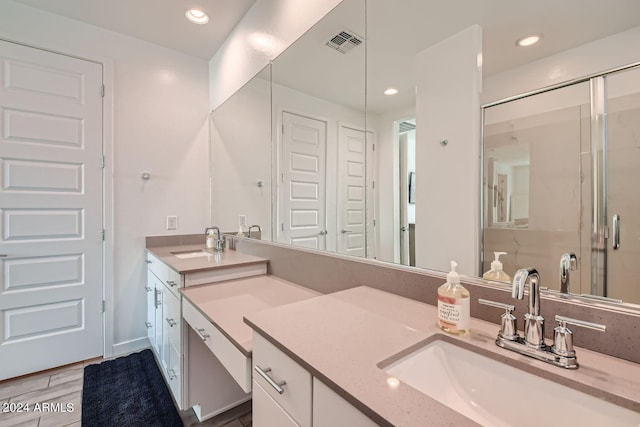 bathroom featuring hardwood / wood-style floors, a shower with door, and vanity