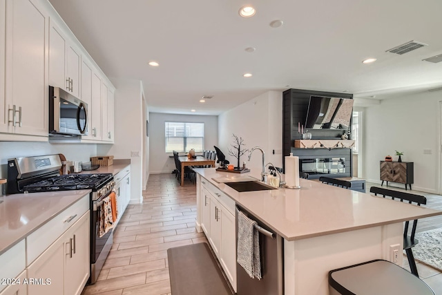 kitchen featuring white cabinetry, appliances with stainless steel finishes, and a kitchen island with sink