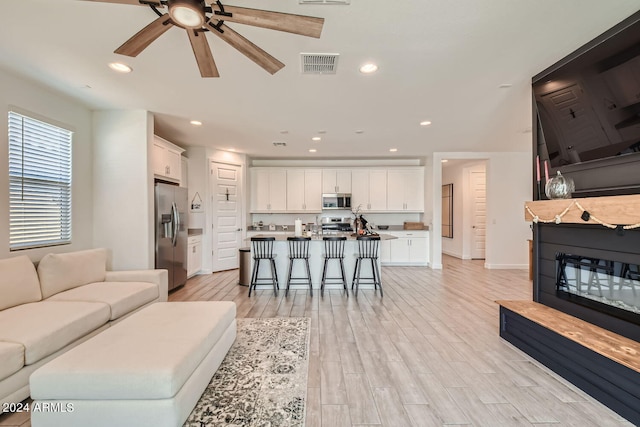 living room featuring light hardwood / wood-style flooring and ceiling fan