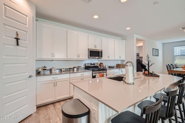 kitchen with an island with sink, white cabinetry, and stainless steel appliances