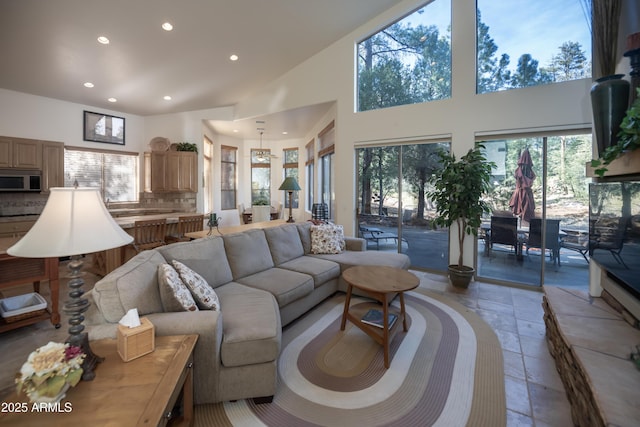 living area with a high ceiling, stone tile flooring, and recessed lighting