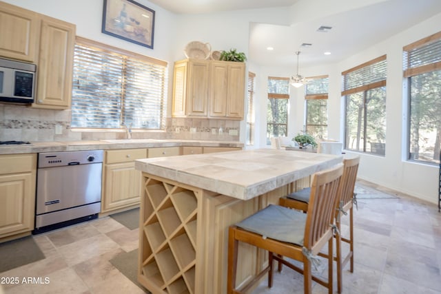 kitchen featuring appliances with stainless steel finishes, a wealth of natural light, a sink, and light brown cabinetry