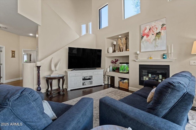 16420 N Thompson Peak Pkwy Unit 1002, Scottsdale, AZ 85260 - living room featuring a towering ceiling, healthy amount of natural light, wood finished floors, a glass covered fireplace, and baseboards