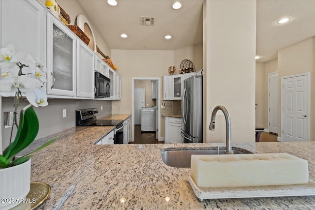16420 N Thompson Peak Pkwy Unit 1002, Scottsdale, AZ 85260 - kitchen with appliances with stainless steel finishes, washer / dryer, a sink, light stone counters, and glass insert cabinets