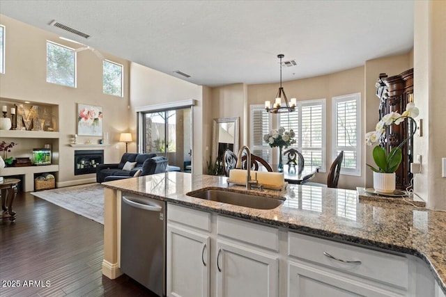 16420 N Thompson Peak Pkwy Unit 1002, Scottsdale, AZ 85260 - kitchen featuring a sink, dishwasher, a glass covered fireplace, a chandelier, and white cabinetry