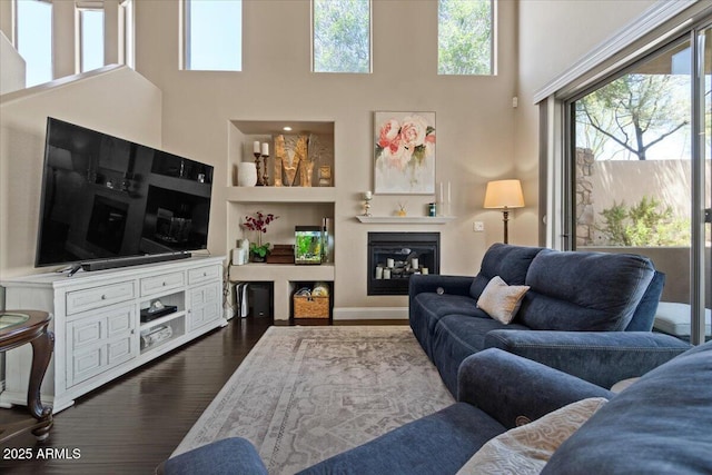 16420 N Thompson Peak Pkwy Unit 1002, Scottsdale, AZ 85260 - living room featuring dark wood-style floors, a high ceiling, a glass covered fireplace, and built in features