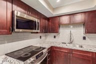 kitchen with decorative backsplash, black range oven, and light stone countertops