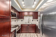 kitchen with rail lighting, stainless steel appliances, a raised ceiling, and sink