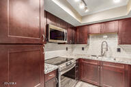 kitchen with sink, light stone countertops, stainless steel appliances, and tasteful backsplash