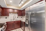 kitchen featuring light stone countertops, backsplash, track lighting, stainless steel appliances, and a tray ceiling