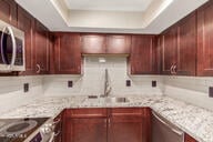 kitchen featuring a tray ceiling, light stone countertops, and stainless steel appliances