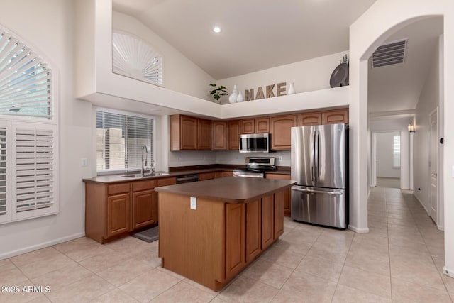 kitchen with visible vents, a kitchen island, a sink, appliances with stainless steel finishes, and dark countertops