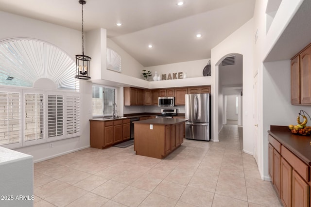 kitchen with a kitchen island, arched walkways, a sink, stainless steel appliances, and dark countertops