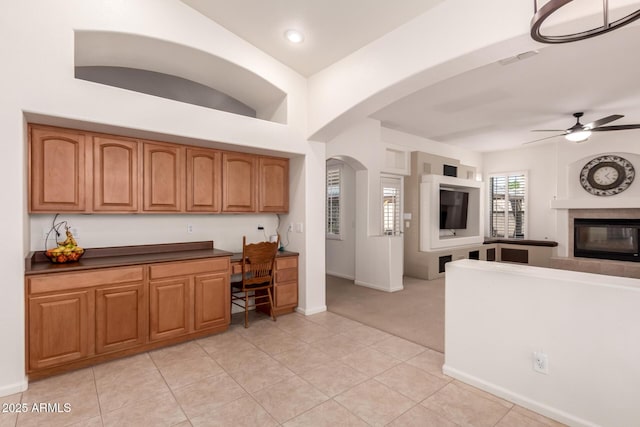 kitchen featuring dark countertops, open floor plan, arched walkways, light tile patterned flooring, and ceiling fan