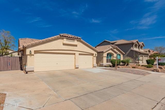 mediterranean / spanish house featuring concrete driveway, a tiled roof, an attached garage, and stucco siding