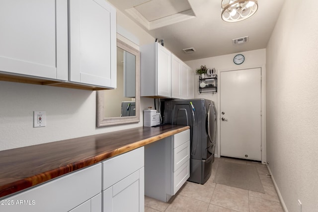 clothes washing area featuring visible vents, cabinet space, washer / clothes dryer, and light tile patterned flooring