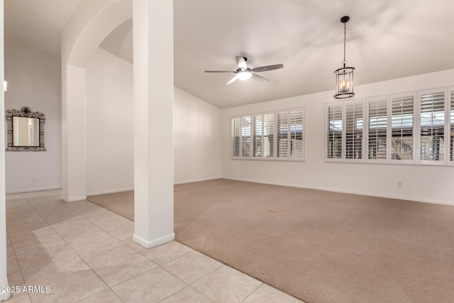 spare room featuring a ceiling fan, arched walkways, light tile patterned flooring, lofted ceiling, and light colored carpet