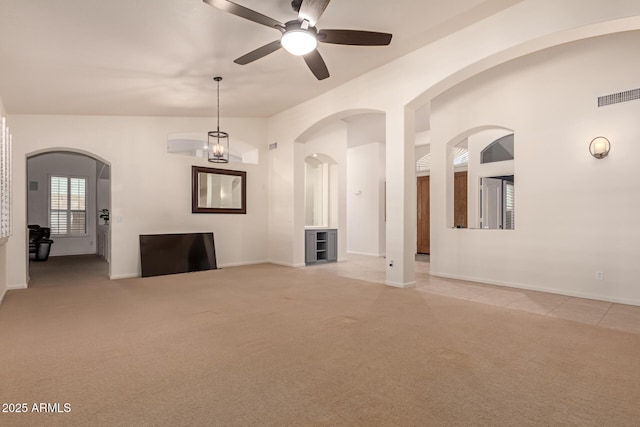 empty room featuring light carpet, visible vents, arched walkways, and lofted ceiling