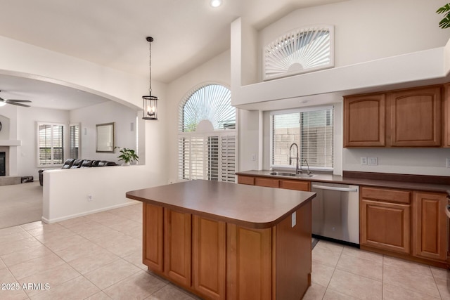 kitchen featuring a sink, stainless steel dishwasher, a glass covered fireplace, a center island, and ceiling fan