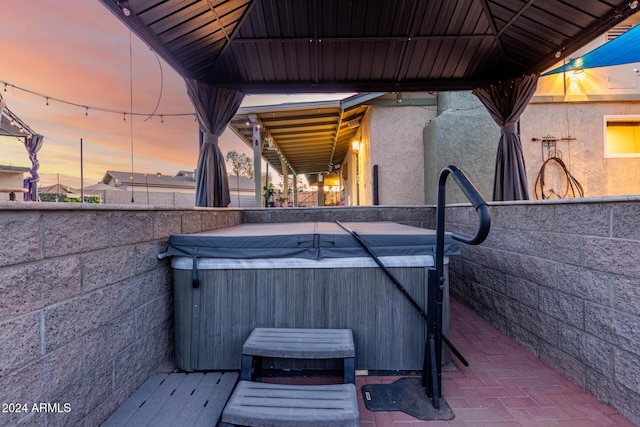 patio terrace at dusk featuring a hot tub