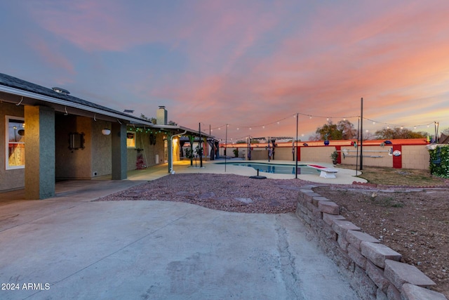 pool at dusk with a patio area