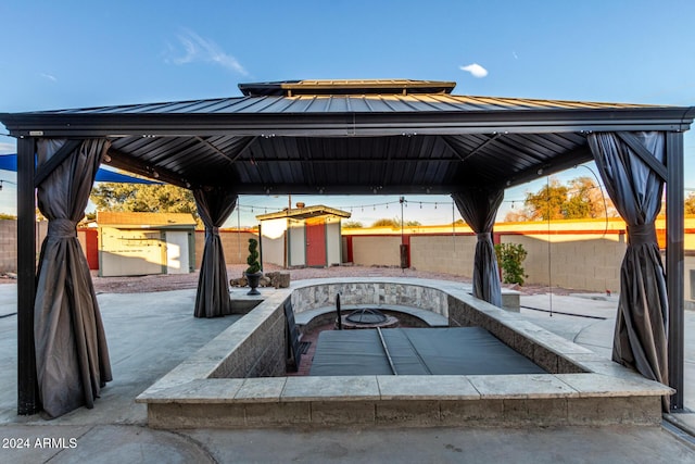 view of patio featuring a gazebo, a storage unit, and an outdoor fire pit