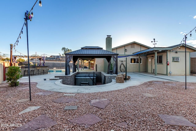 back of house featuring a gazebo, a patio area, exterior bar, and a hot tub