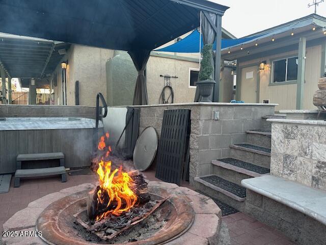 view of patio / terrace with a hot tub and an outdoor fire pit