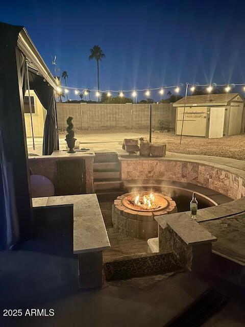 patio at twilight featuring a shed and a fire pit