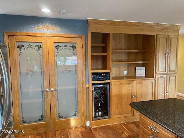 kitchen featuring french doors, wine cooler, stainless steel fridge, dark stone countertops, and wood-type flooring