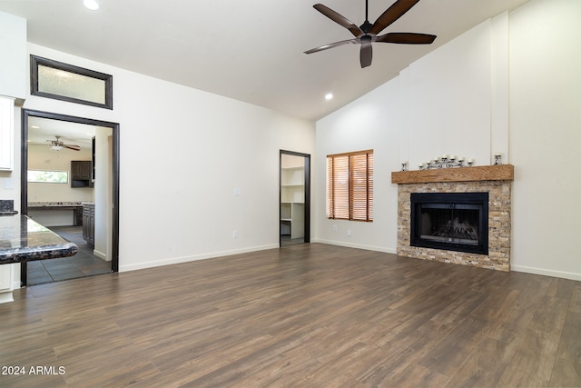 unfurnished living room featuring ceiling fan, dark hardwood / wood-style floors, a stone fireplace, and high vaulted ceiling