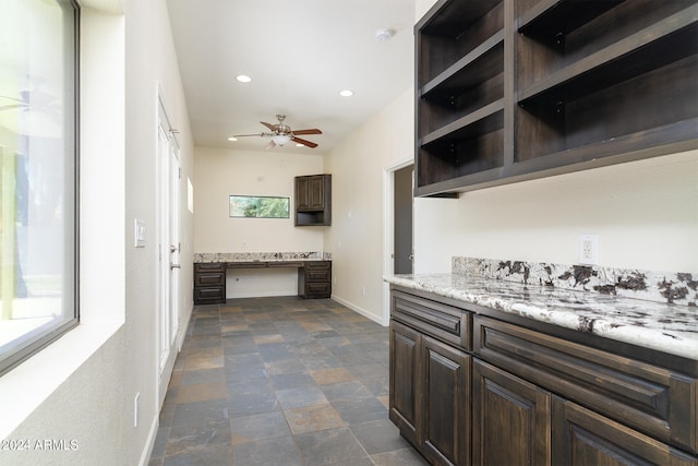 kitchen with dark brown cabinets, built in desk, ceiling fan, and plenty of natural light