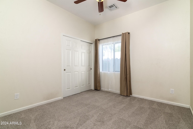 unfurnished bedroom featuring light carpet, ceiling fan, and a closet