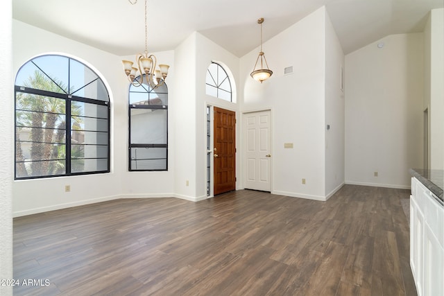 foyer entrance with dark hardwood / wood-style flooring, high vaulted ceiling, and a notable chandelier