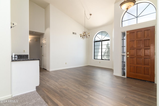 foyer featuring dark hardwood / wood-style floors, an inviting chandelier, and high vaulted ceiling