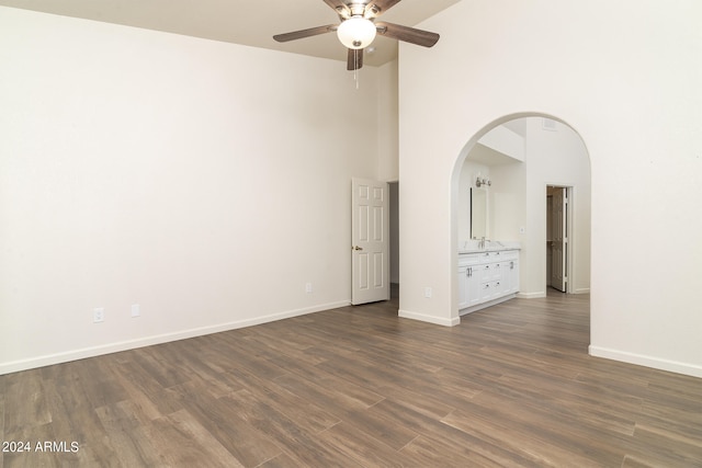 spare room featuring dark hardwood / wood-style flooring, ceiling fan, and a high ceiling