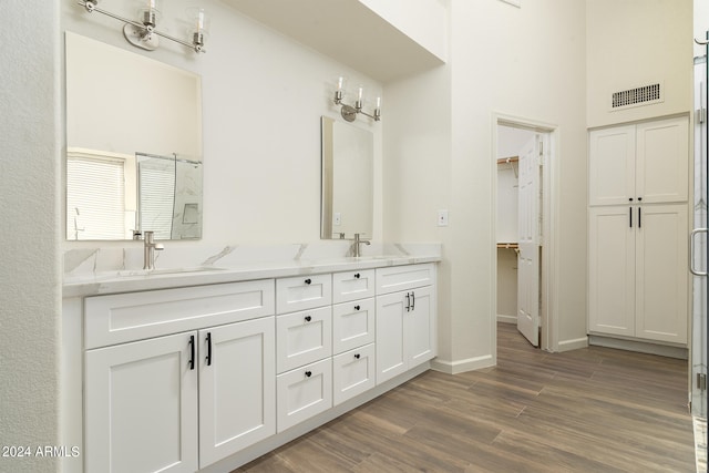 bathroom with walk in shower, wood-type flooring, a high ceiling, and vanity