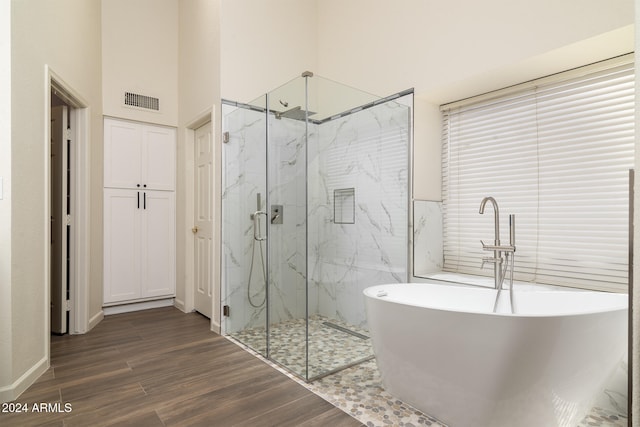 bathroom with separate shower and tub, wood-type flooring, and a towering ceiling