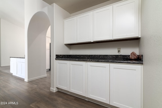 kitchen featuring dark stone counters, dark hardwood / wood-style floors, and white cabinetry