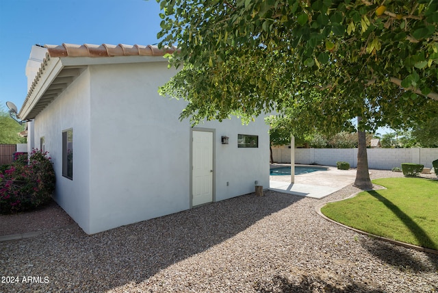 rear view of house with a fenced in pool and a patio area