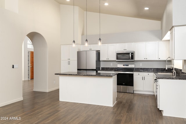 kitchen featuring appliances with stainless steel finishes, decorative light fixtures, high vaulted ceiling, a center island, and white cabinets